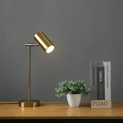 Modern nordic decorbites golden table lamp with a brass finish, adjustable cylindrical head, and slender stem for bedroom use