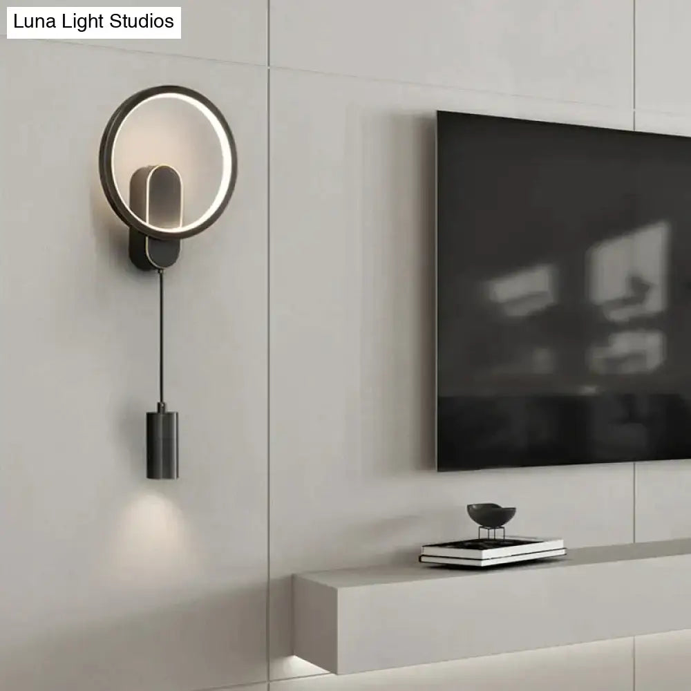 Modern nordic led wall lamp in black gold with a circular illuminated ring and cylindrical pendant for bedroom use
