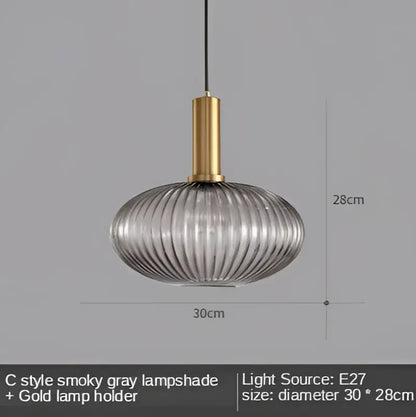 A sleek smoky gray ribbed glass led pendant light with a polished gold metal holder for modern dining rooms