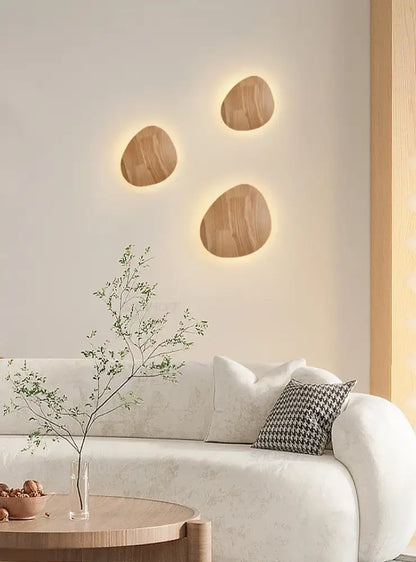Three oval-shaped modern nordic eclipse wooden wall lamps with warm glowing backlight for bedroom use