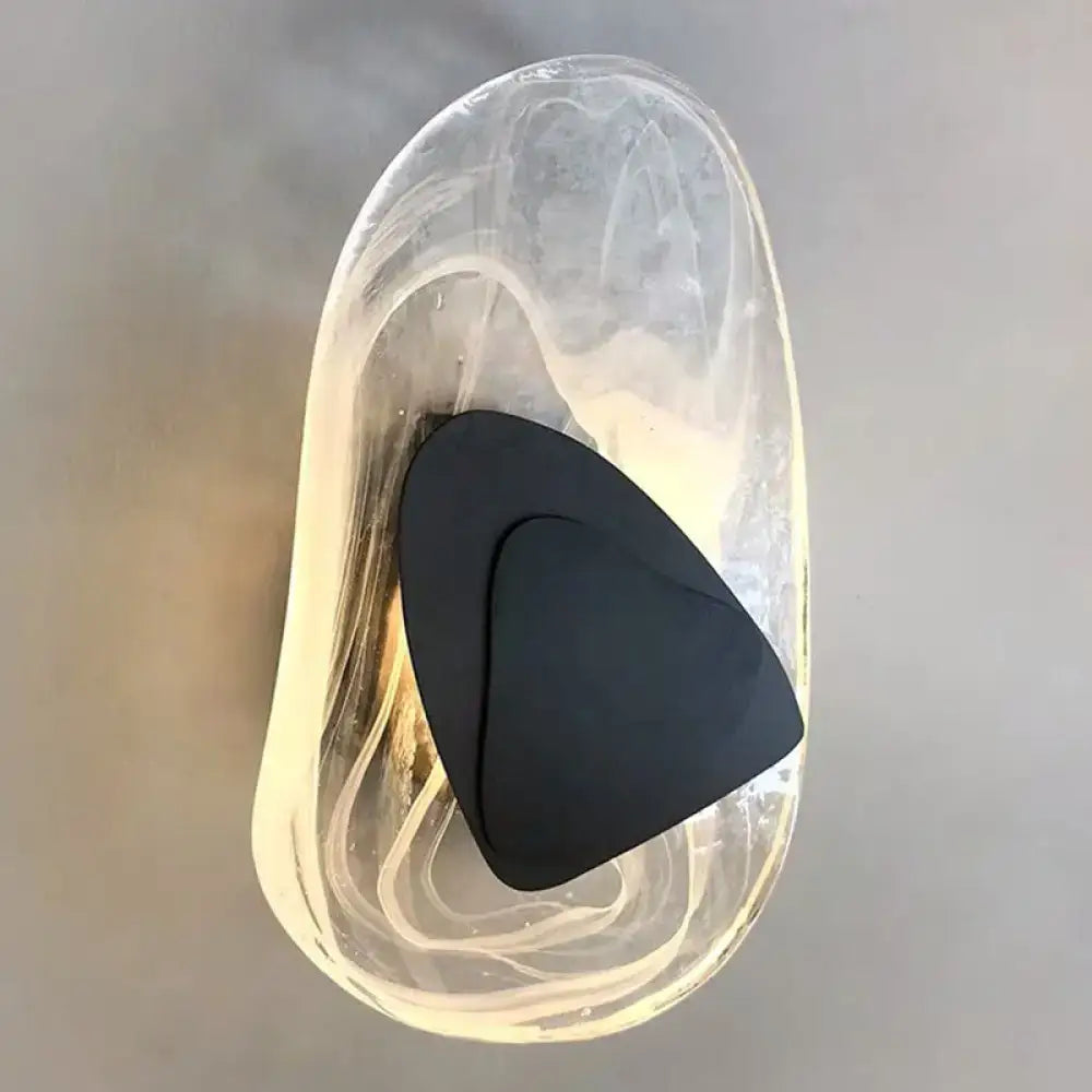 A sleek black metallic modern nordic sconce light fixture with a triangular design inside a translucent glass container
