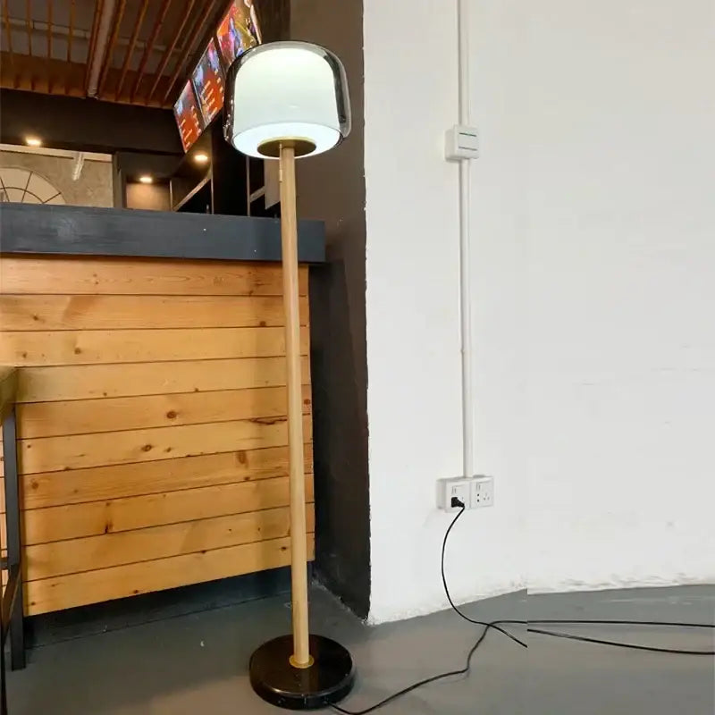 Modern nordic wood and glass floor lamp with a sleek white glass shade and slender bamboo pole base for living room
