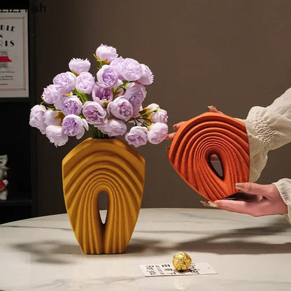 Modern orange geometric ceramic vase with sculpted arch and ridges holding light purple flowers for living room decorbites geometric ceramic use