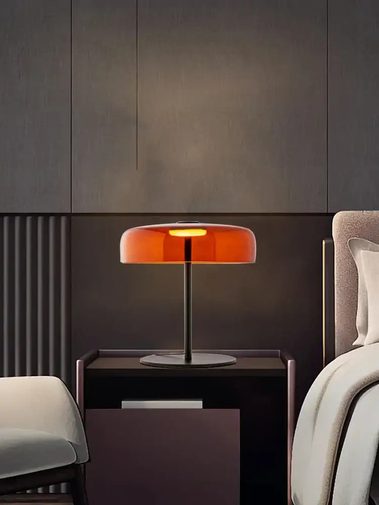 A modern orange glass table lamp with a translucent shade and slender black metal base for minimalist decorbites decor