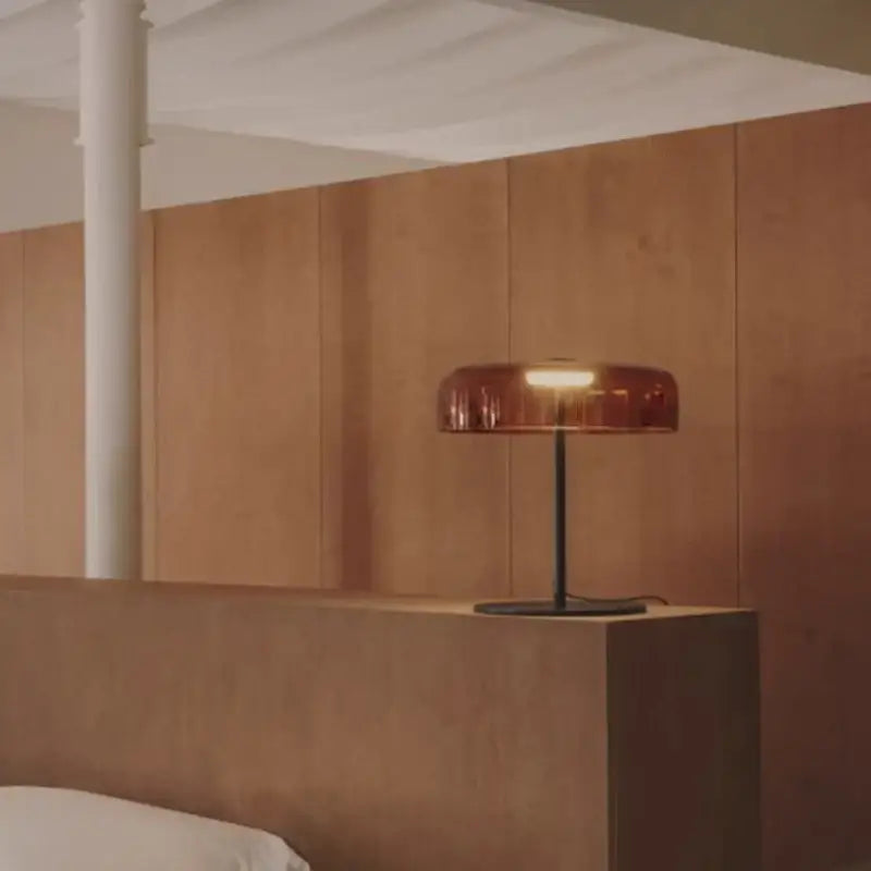 A modern orange glass table lamp with amber-tinted shade and black metal base ideal for minimalist bedroom decorbites