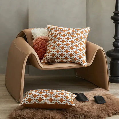 Tan leather armchair with sleek curved design and modern orange and white decorbites jacquard crochet pillow covers