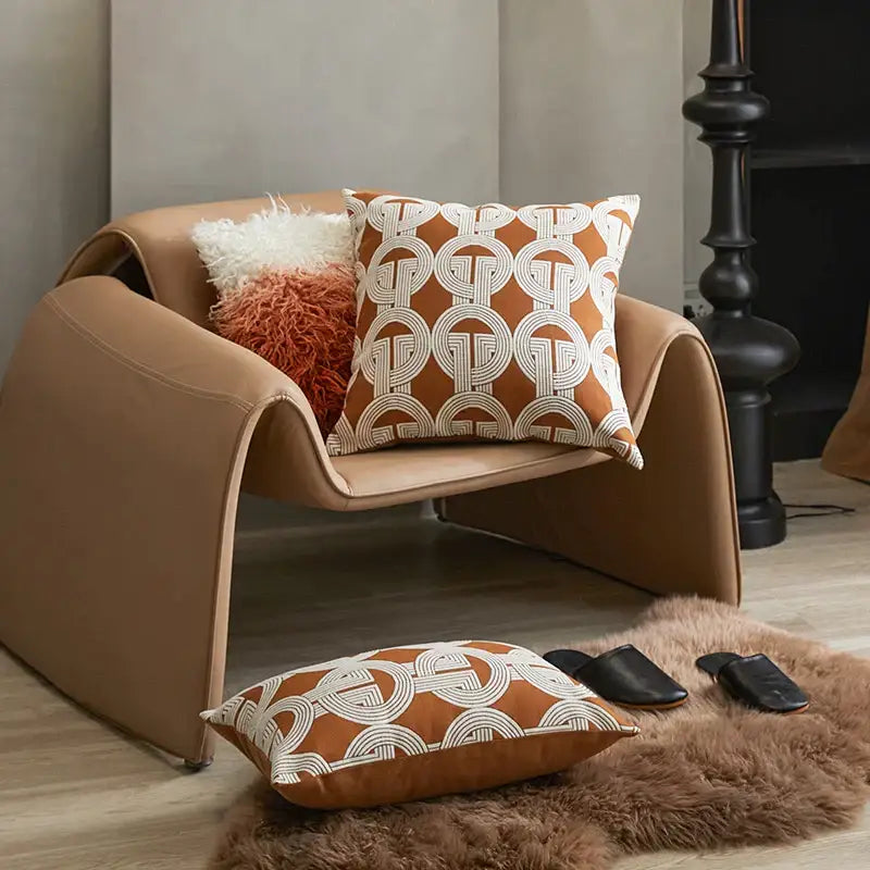Tan leather armchair with curved modern design featuring decorbites jacquard crochet pillow covers in orange and white
