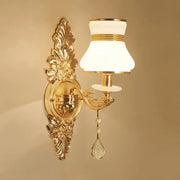 Modern ornate gold wall light with frosted glass shade and crystal teardrop designed as a bedroom sconce