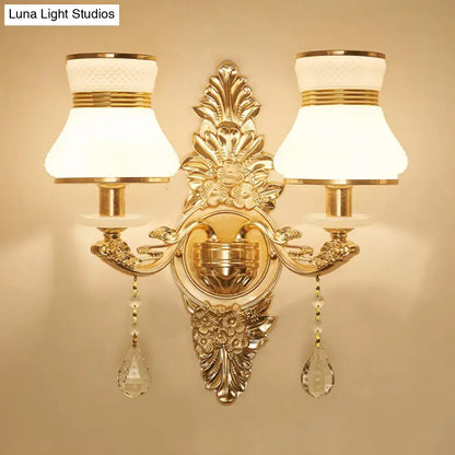 Modern ornate gold wall light with frosted glass shade featuring crystal teardrop pendants for bedroom sconce use