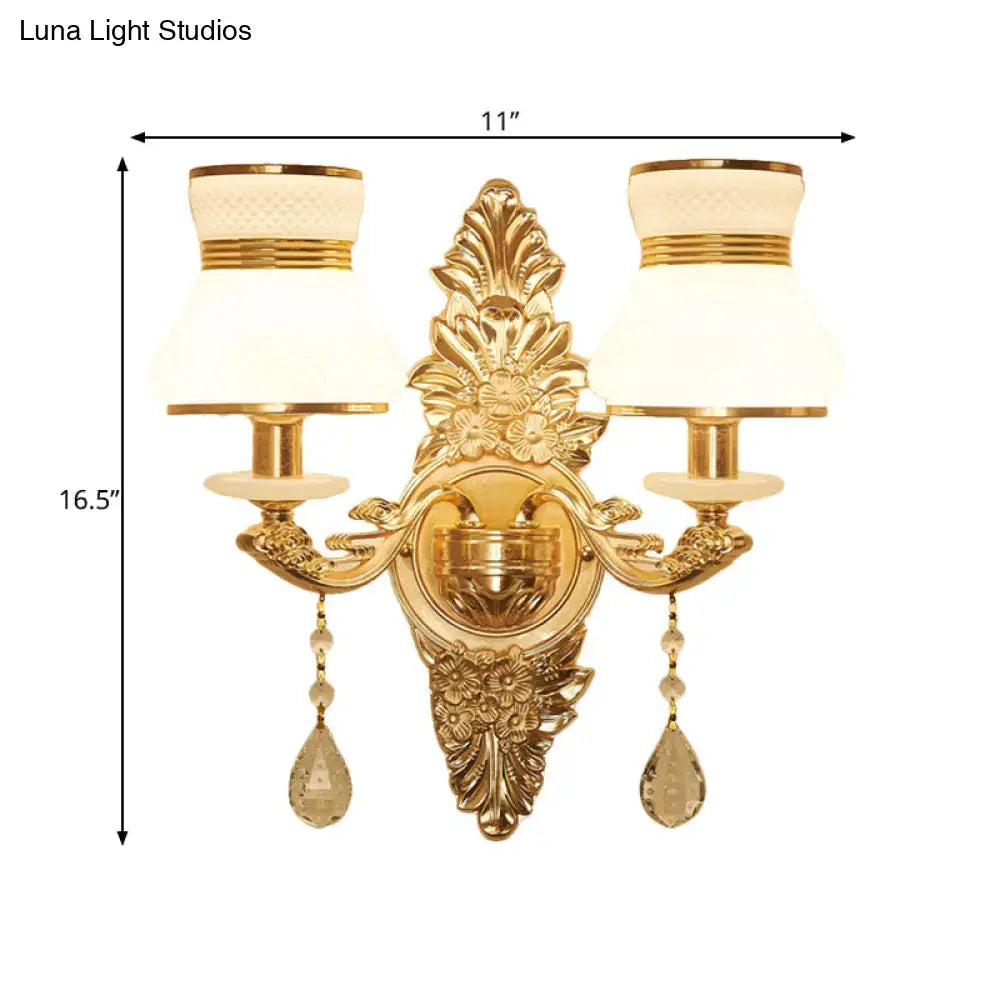 Modern ornate gold wall light with frosted glass shade featuring two cream lampshades and crystal teardrop pendants