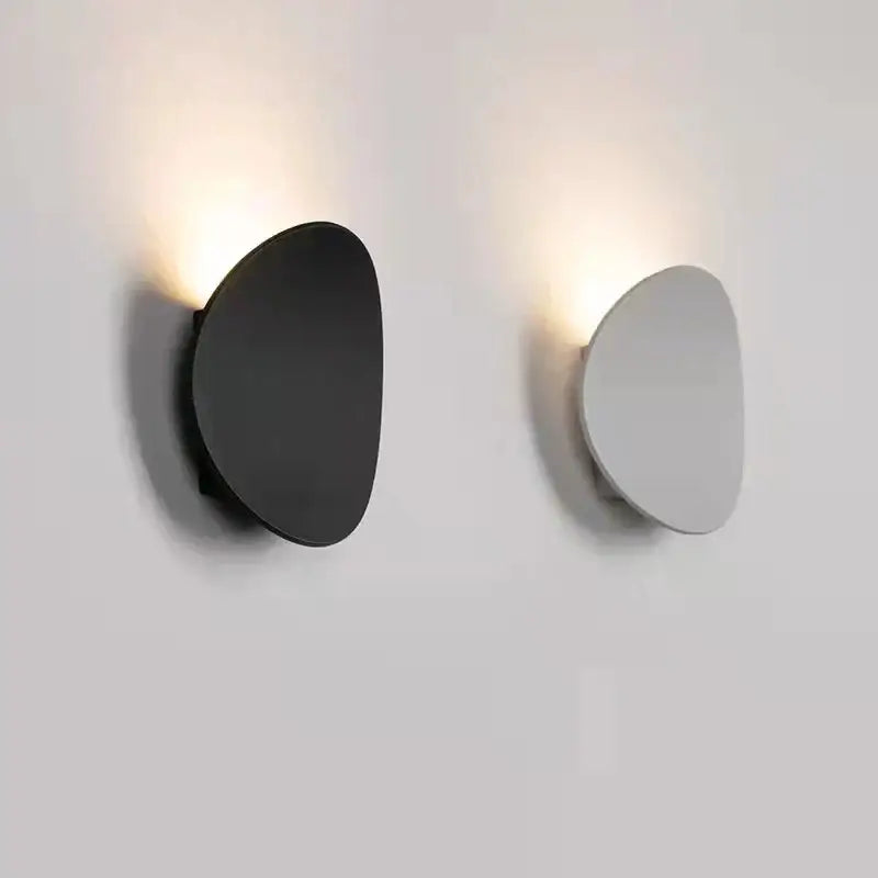 Two modern oval gray and dark gray led wall lamps with matte finish emit warm glow for garden lighting