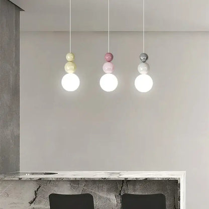 Three modern metal pendant lights with stacked globe design in pastel yellow pink and matte gray light color options
