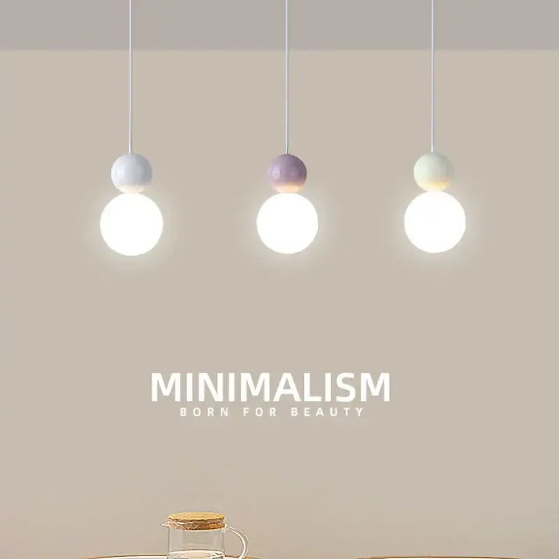 Three minimalist pendant lights with spherical white glass bulbs and pastel lavender and cream decorbites cream nordic finish