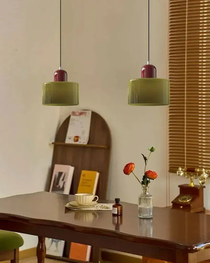 Two olive green cylindrical cord pendant lights with burgundy tops in modern pastel stained glass kitchen set