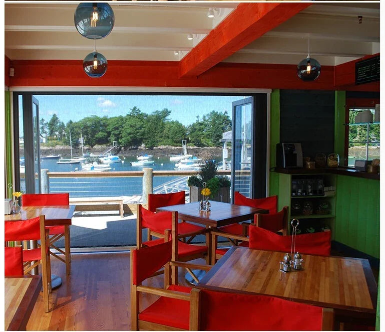 Red upholstered chairs with wooden frames complement modern pendant lights featuring multicolored glass for dining rooms