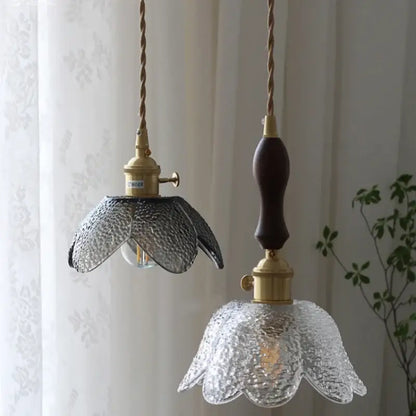 Two pendant lamps with textured clear glass LED flower shades and brass hardware, suspended by twisted rope cords