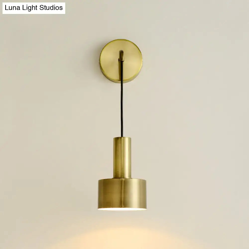 Brass-finished minimalist wall sconce with cylindrical shade and black cord for modern pink and brass bedside reading e14 e26 e27