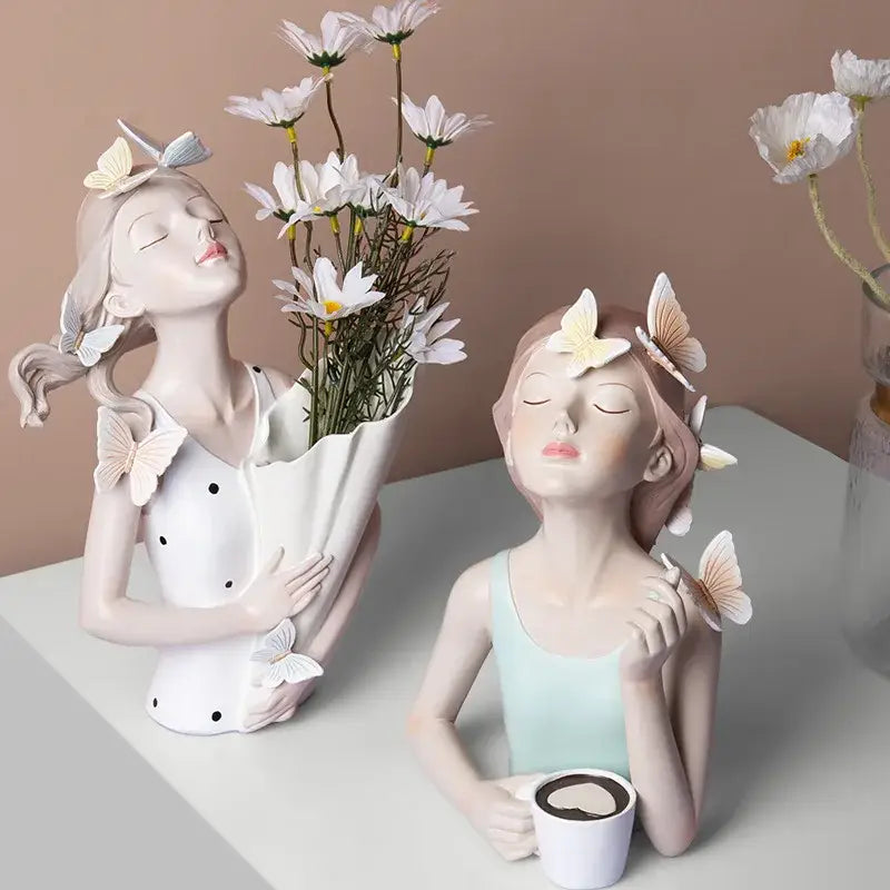 Two butterfly girl resin figurines with closed eyes holding daisies and coffee cup on gold tray decor