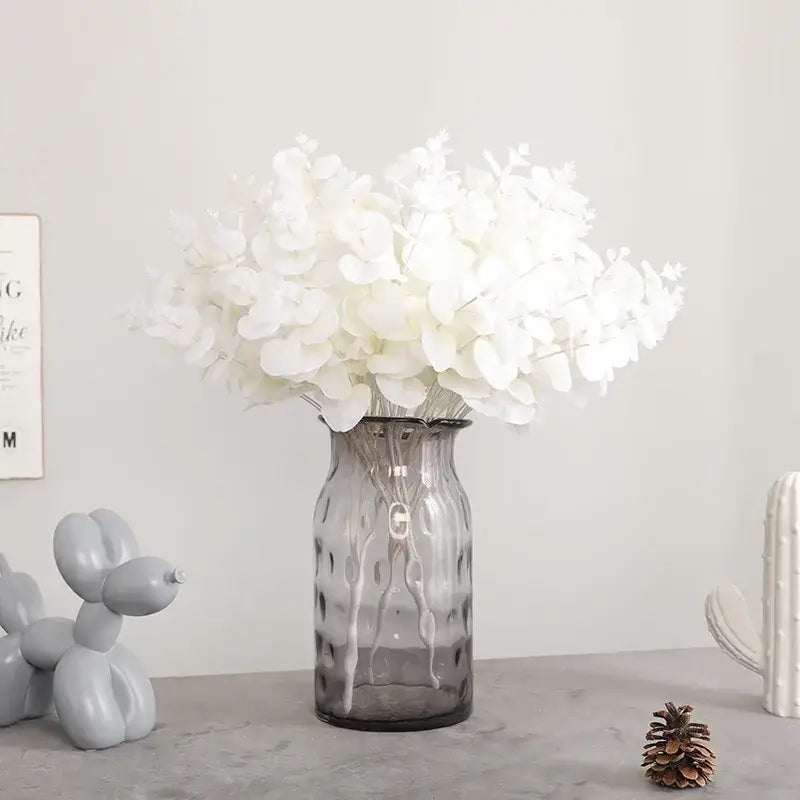Modern pink living room glass vase with translucent gray ribbed surface holding a white eucalyptus flower arrangement