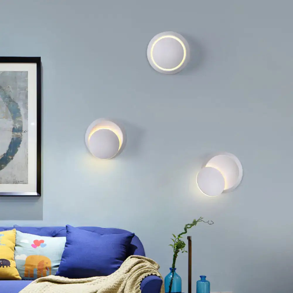 Three modern white circular wall sconces with glowing led rings.