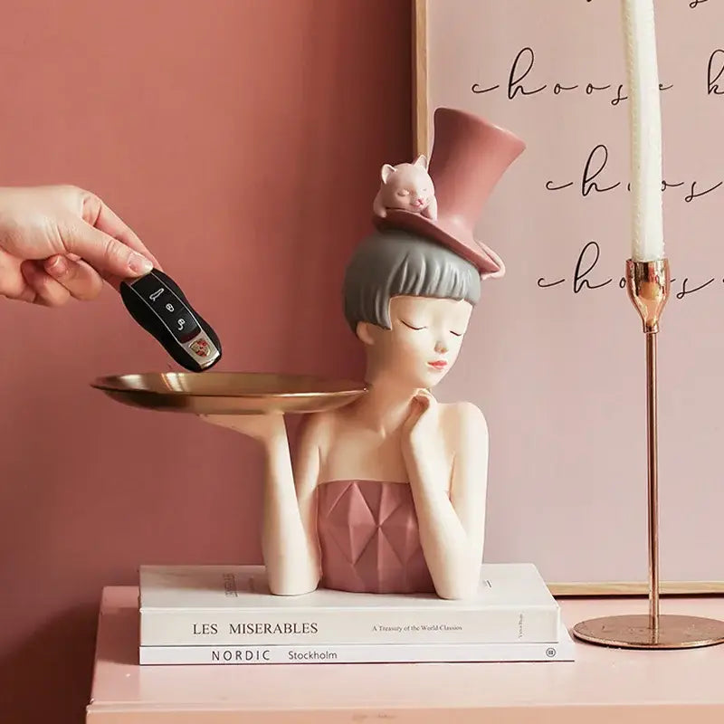 Pastel pink resin sculpture tray featuring an elegant woman with gray hair and matching top hat for home decor by decorbites