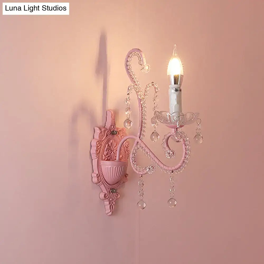 Modern pink metallic scroll arm wall lamp with crystal droplets and candle-style bulb for elegant bedroom sconce lighting