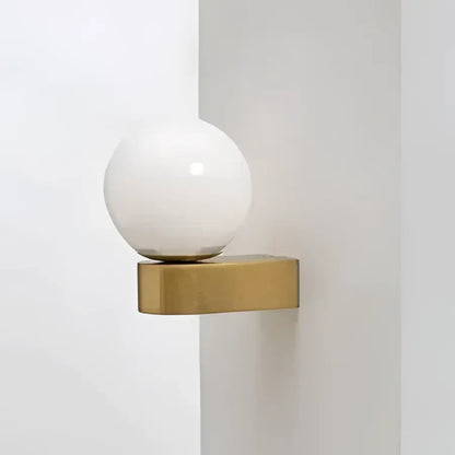 A sleek spherical white glass ball led wall lamp on a minimalist gold-toned decorbites glass ball bracket