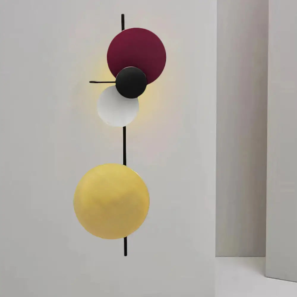 Modern geometric circular wall mount light with stacked burgundy, black, white, and yellow shades for living room