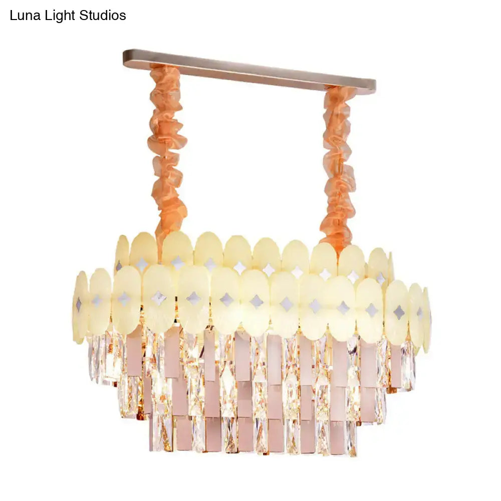 A modern pink and yellow dining room pendant chandelier with rose gold frame and clear crystal cascading tiers
