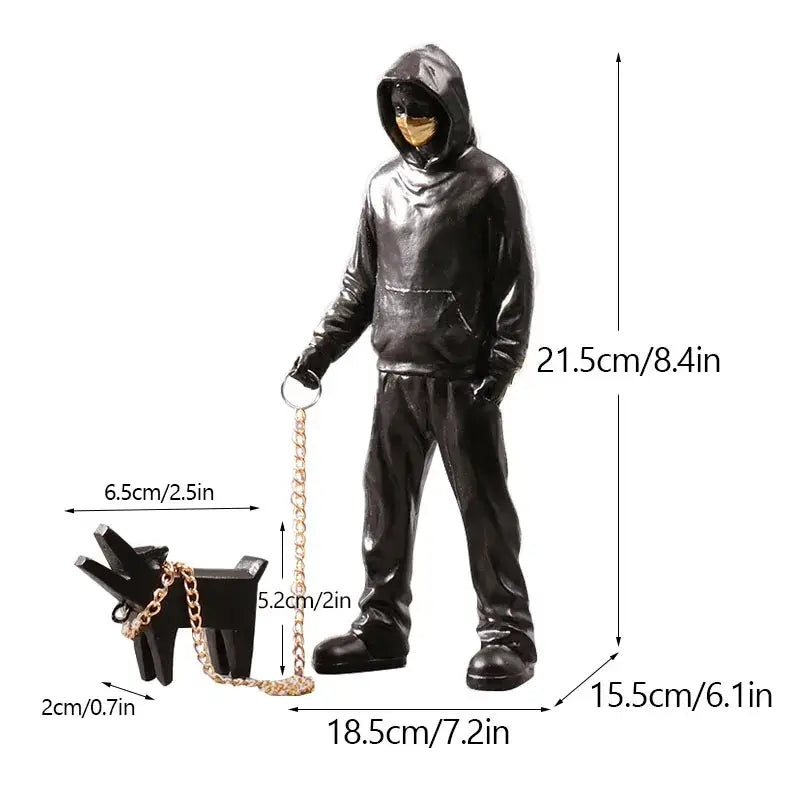 Black glossy decorbites dog sculpture of hooded figure with gold mask holding leash attached to small black dog for living room decor