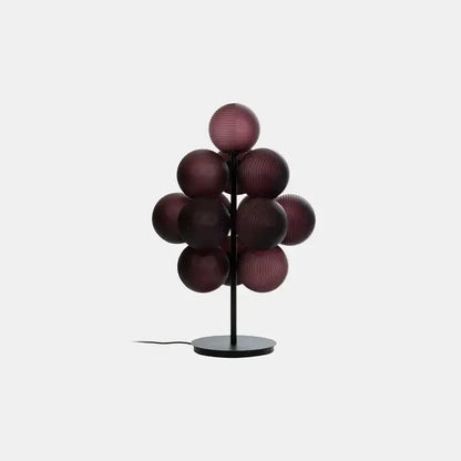 A modern floor lamp with deep burgundy decorbites glass bubble spheres on a slender black metal stem and base
