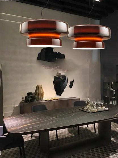 Two tiered amber and metallic decorbites italian glass pendant lights hang above a dining table in modern style