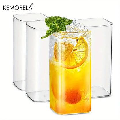 Modern rectangular clear glass highball glasses set featuring one glass filled with orange beverage and lemon garnish