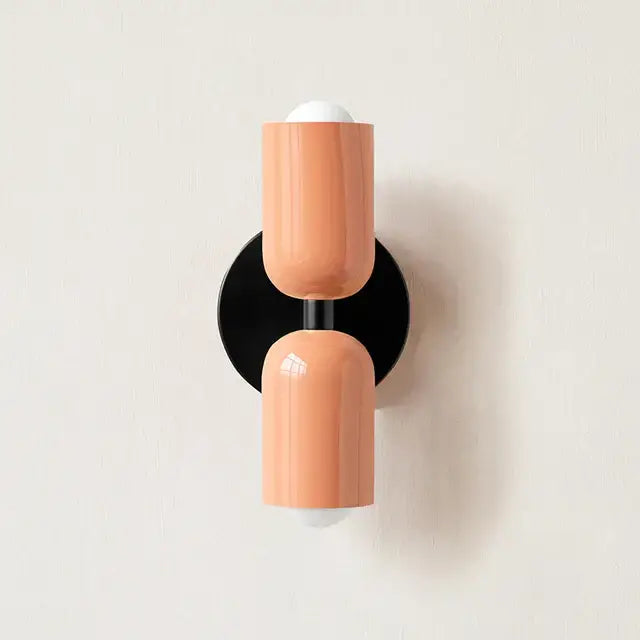 Modern coral-colored cylindrical led wall lamp with black base and white bulb caps for bedroom and living room decor