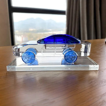 A sleek crystal car model with vibrant blue glass accents on roof and wheels for modern office table decor