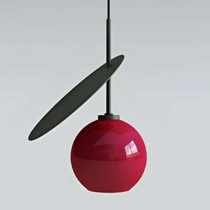 A modern red glass cherry led pendant light with a glossy spherical shade and matte black accents for dining room decorbites