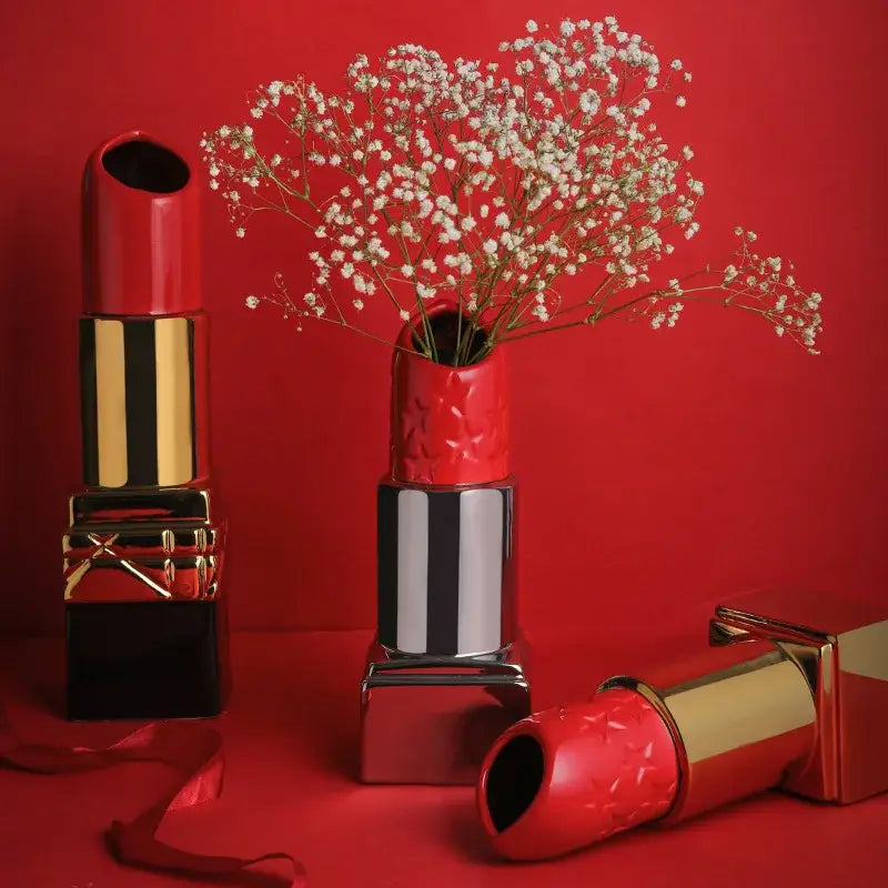Modern red decorbites lipstick shape ceramic vase with textured surface and gold accents holding white baby’s breath flowers