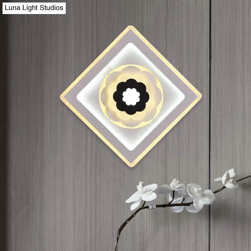 Modern rhombus bloom pattern sconce light with black and white floral center, soft yellow accents, and bulb base design