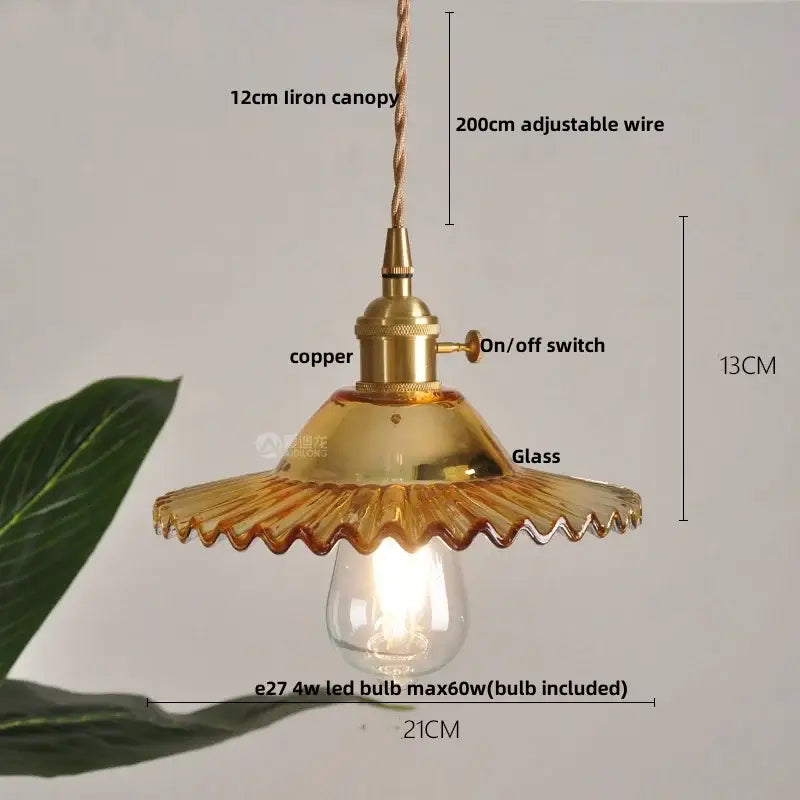 A vintage-style pendant light with brass finish, amber scalloped glass shade, and clear glass led bulb for decorbites