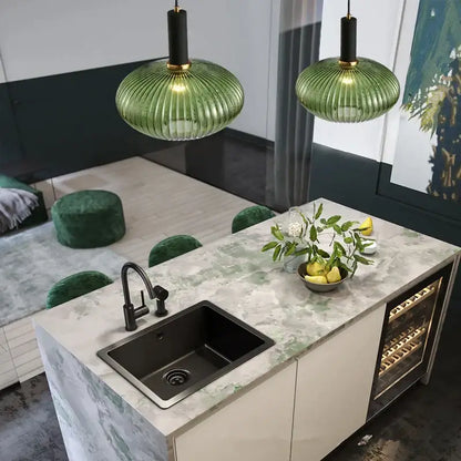 Green ribbed glass colorful led pendants with black and gold fixtures hang as modern light chandeliers above kitchen island