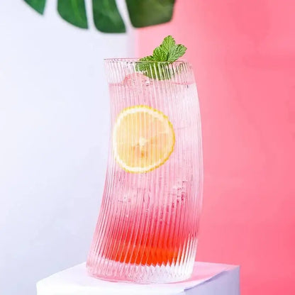 Modern ribbed sail-shaped glass cups feature a tall curved design with vertical ridges holding a pink red drink