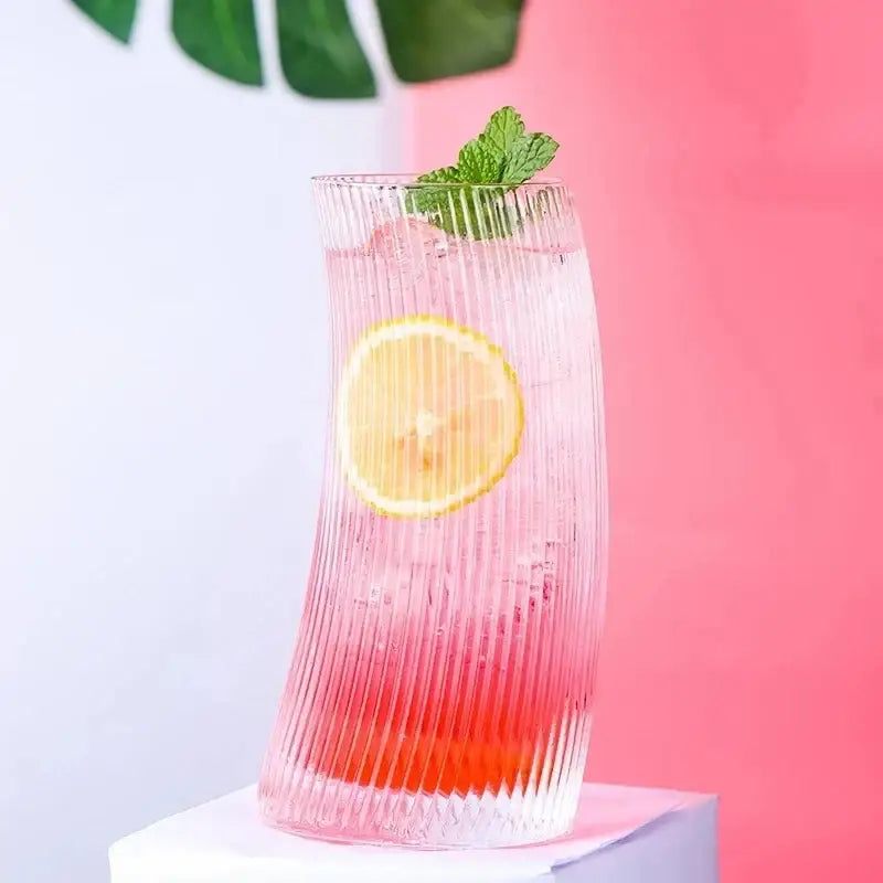 Modern ribbed sail-shaped glass cups feature a tall curved design with vertical ridges holding a pink red drink