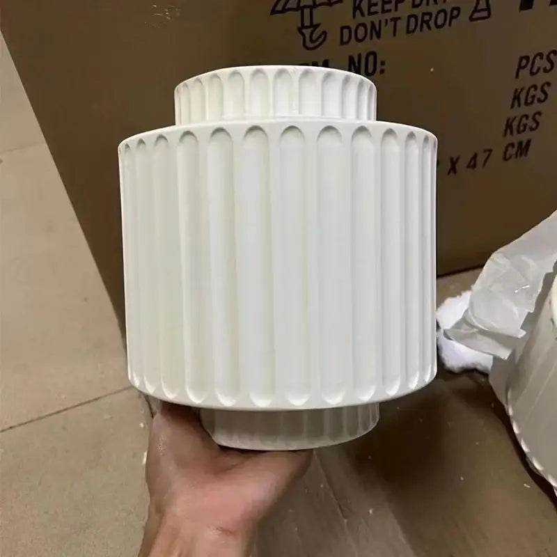 Modern ridged cream white resin wall lamp featuring a white ceramic vase with vertical fluted ridges and tiered design