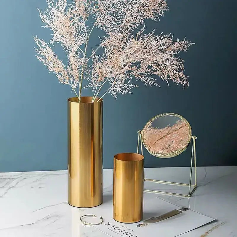 Modern ridged gold plated cylinder vase with sleek reflective surface holding pinkish-white dried branches for decorbites decorbites gold plated