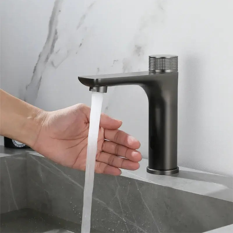 Modern matte black bathroom faucet with textured diamond-patterned knob complements ridged gold sensor mixer tap design