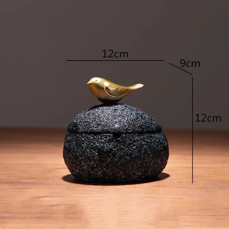 A small round black stone tissue box with a decorbites golden bird resin figurine for living room decor