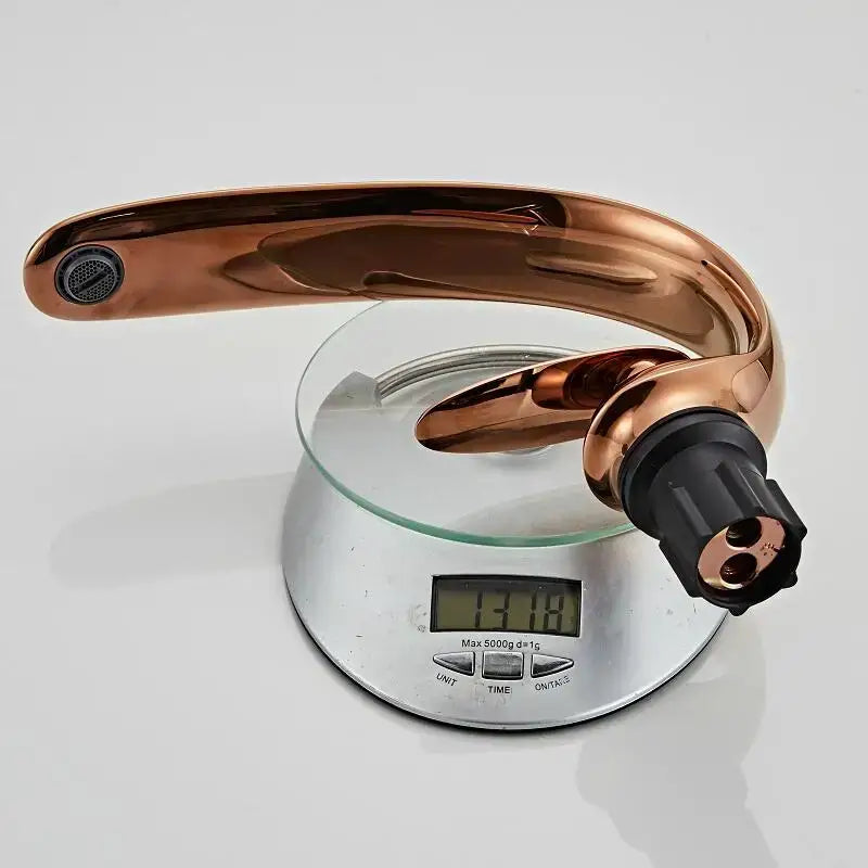A modern rose gold and black brass decorbites basin faucet with a sleek curved spout and textured handle base