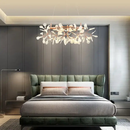 Modern rose gold pendant light with copper-toned frame and white leaf-shaped glass light sources above bed