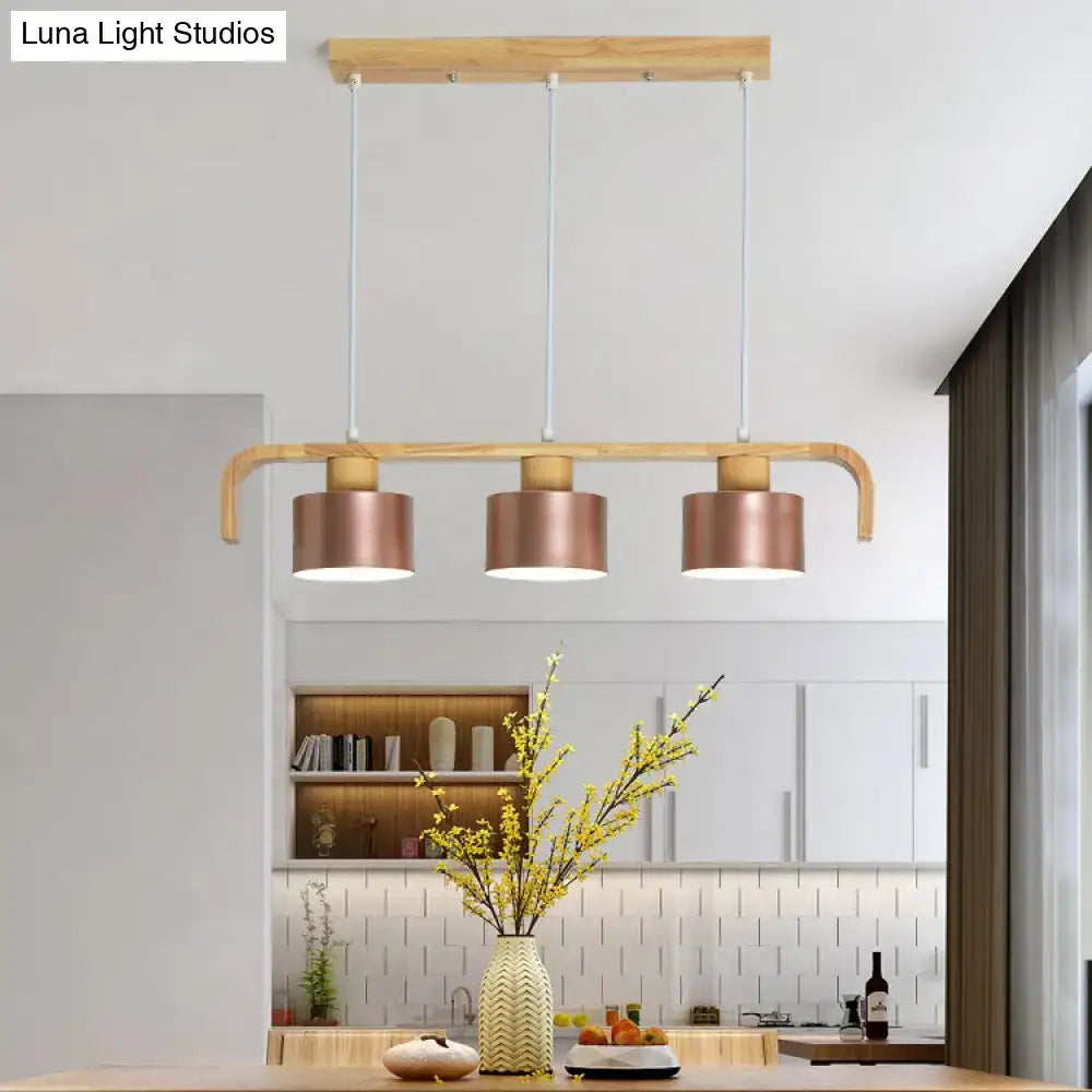 Modern rose gold drum island chandelier with three copper cylindrical shades and light wood frame for dining table lighting