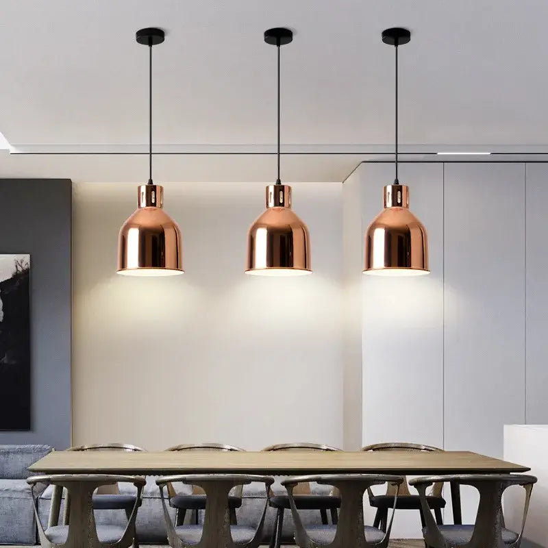 Three sleek rose gold pendant lights with black cords hang above a dining table for modern decorbites decor